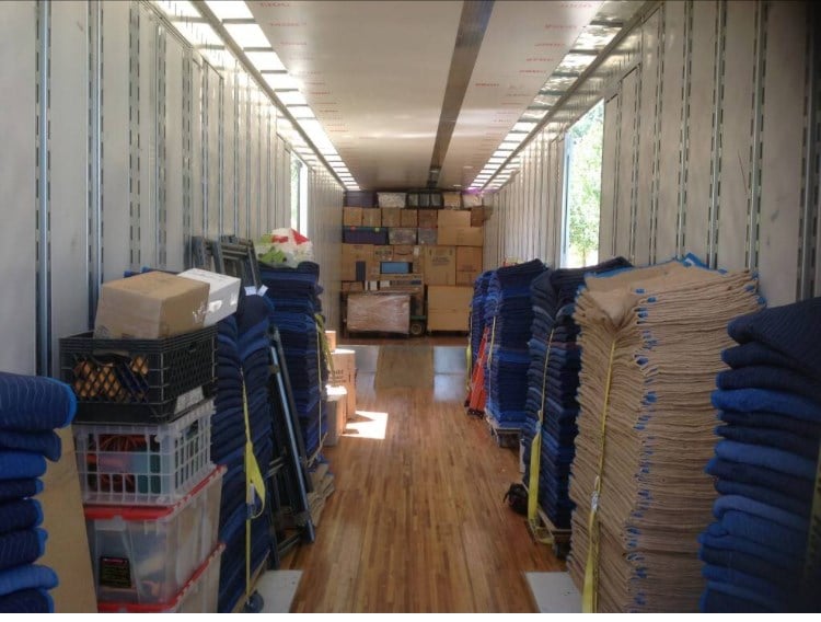 Movers wrapping a sofa in protective blankets before loading