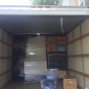 Two-man crew carrying boxes down apartment stairs